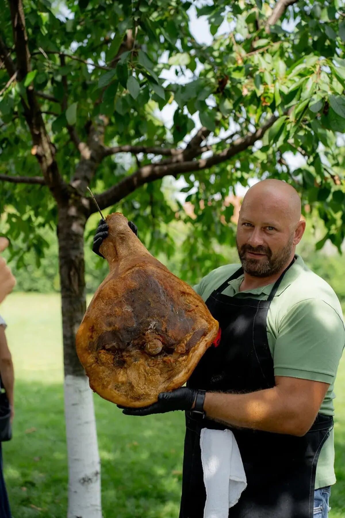 Raul ținând un jambon maturat, în livadă