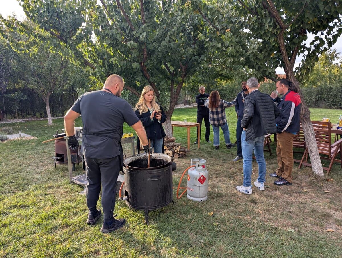 Oameni gătind împreună pe foc, la un atelier în grădină